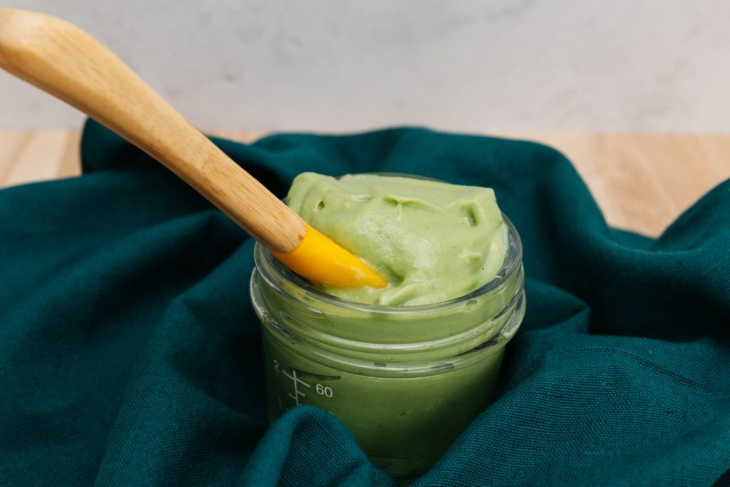 avocado puree with a baby spoon on the table cloth