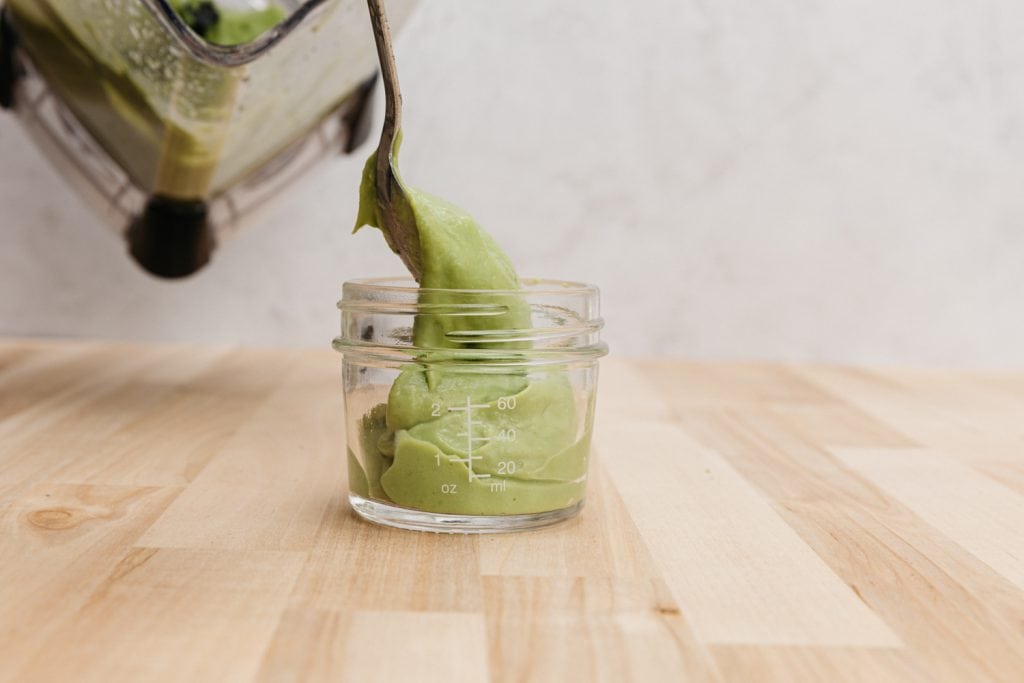 transfering avocado puree into a glass jar