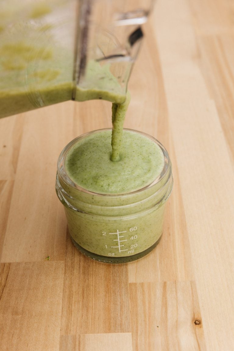 pouring broccoli baby food puree into a glass container